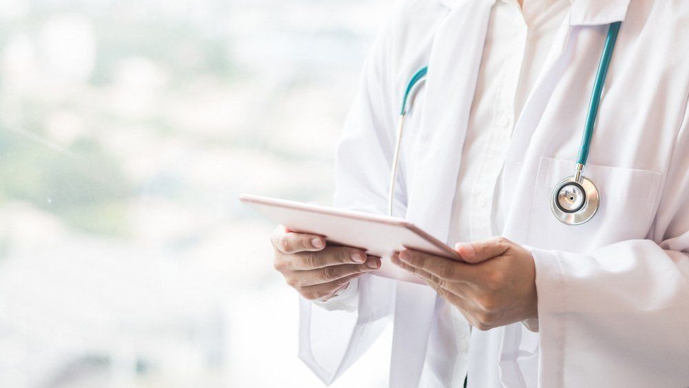 Doctor in White Coat Holding a Tablet — One Stop Medical in Mackay, QLD