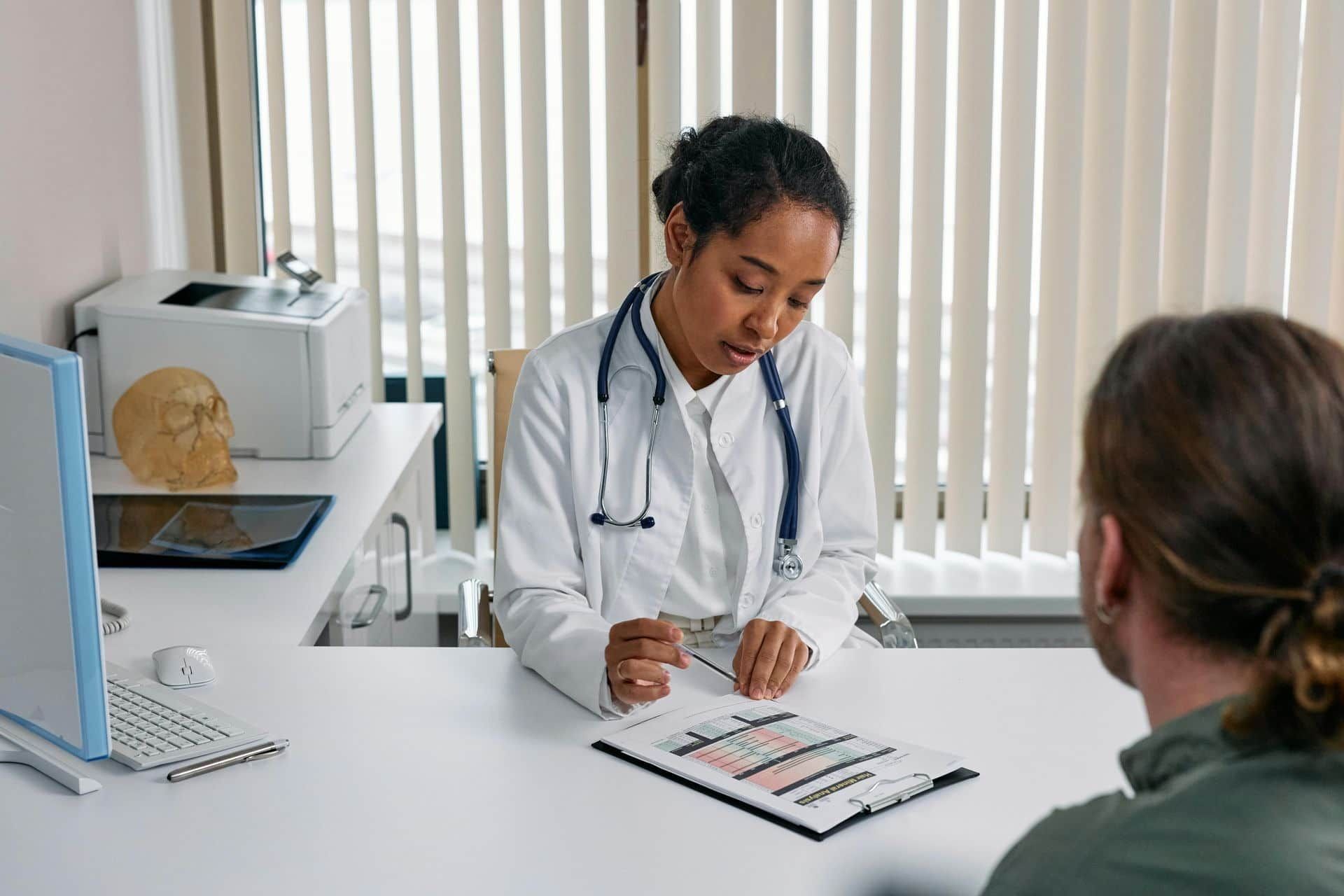 Doctor in White Coat Reviews Paperwork with A Patient — One Stop Medical in Mackay, QLD