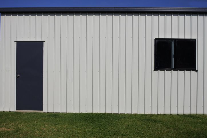 Brick house with dark siding and black window frames. Cloudy sky in background.