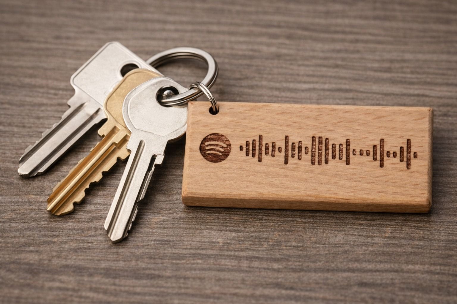 Chiavi e portachiavi in legno con codice Spotify su una superficie di legno.