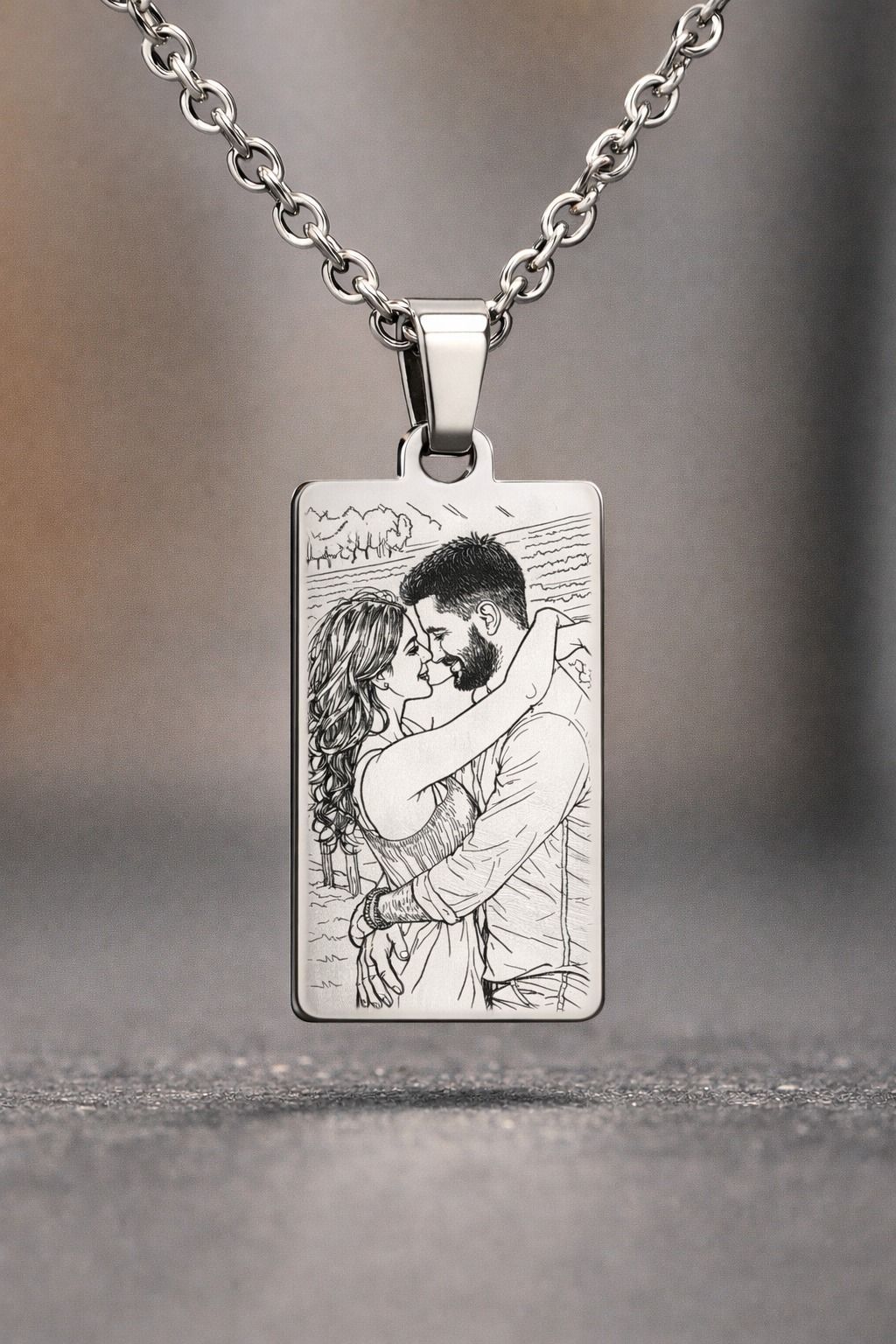 Ciondolo in argento con foto incisa di una coppia che si abbraccia e si bacia, appeso a una catena.
