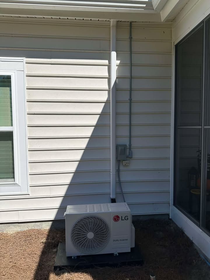 LG air conditioning unit installed outside a house with gray siding and electrical conduit.