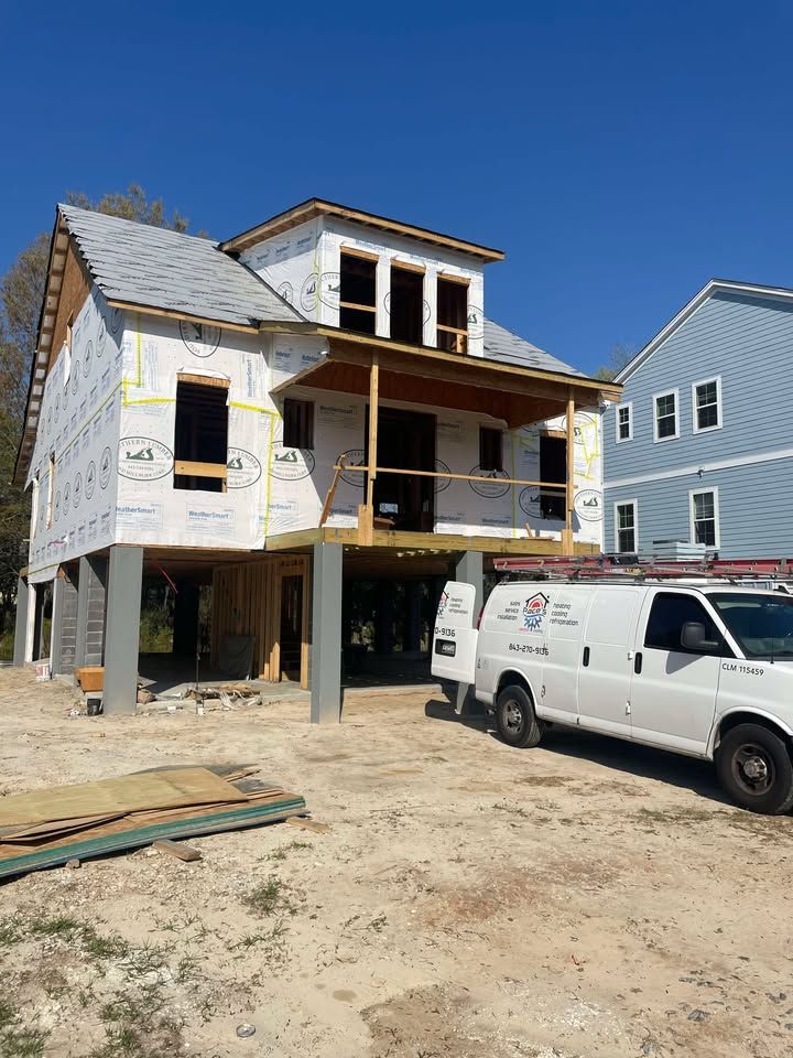 House under construction, elevated on stilts, with a white work van parked nearby.