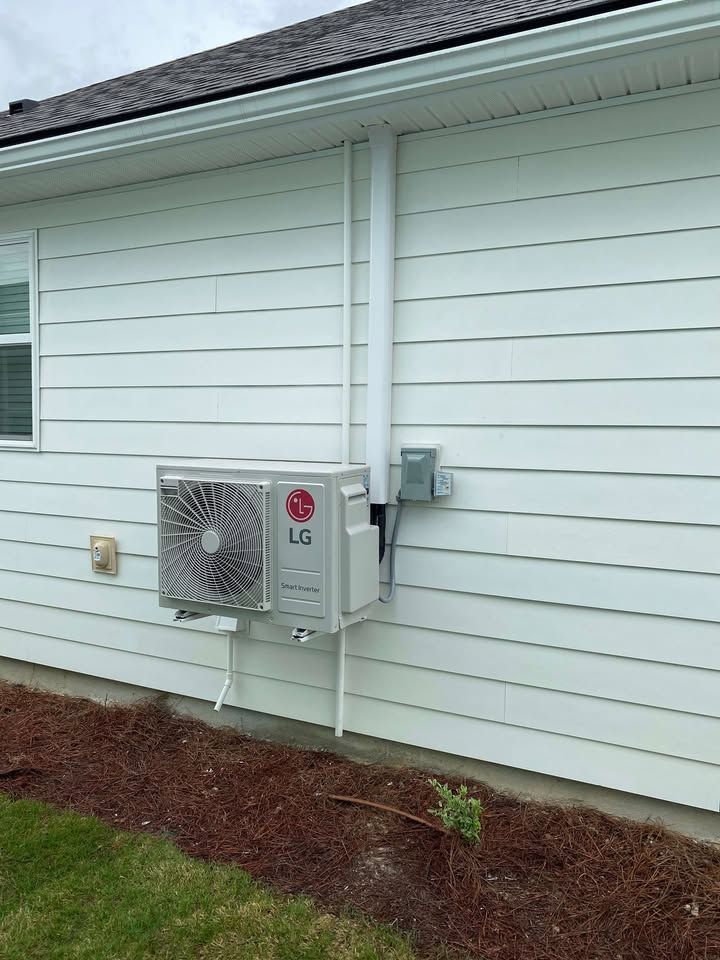 LG air conditioning unit installed on a white house exterior with piping.