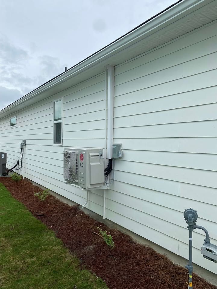 White house exterior with AC unit mounted on the wall. A gas pipe is in the foreground.