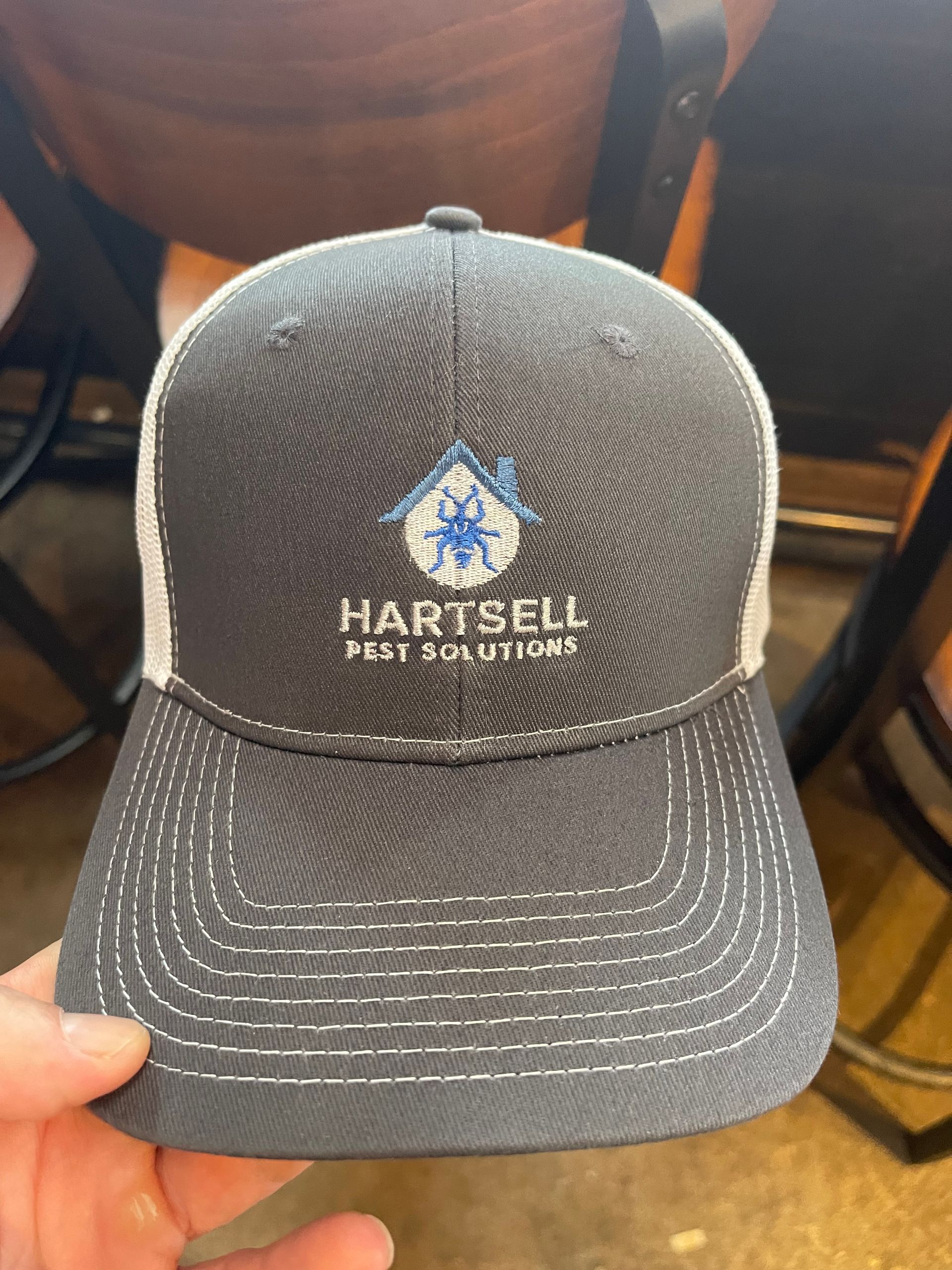 Person in hazmat suit steam cleans carpet in room with plants and wooden shelves.