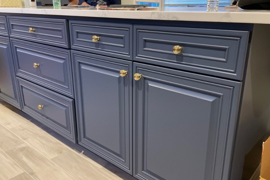 Blue kitchen cabinets with gold knobs; close-up view, showing drawers and doors.
