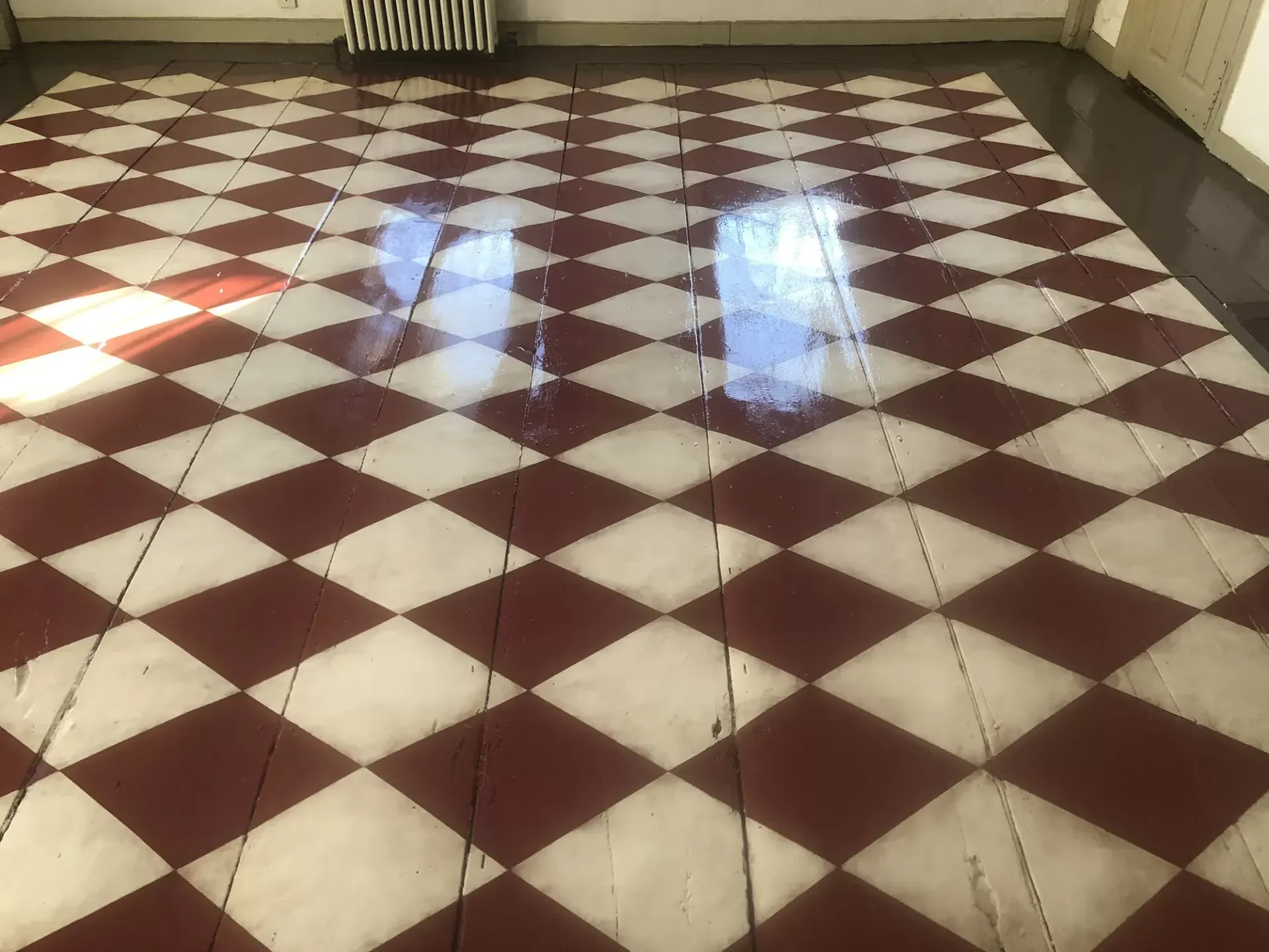 Red and white checkered floor in a room, reflecting sunlight.