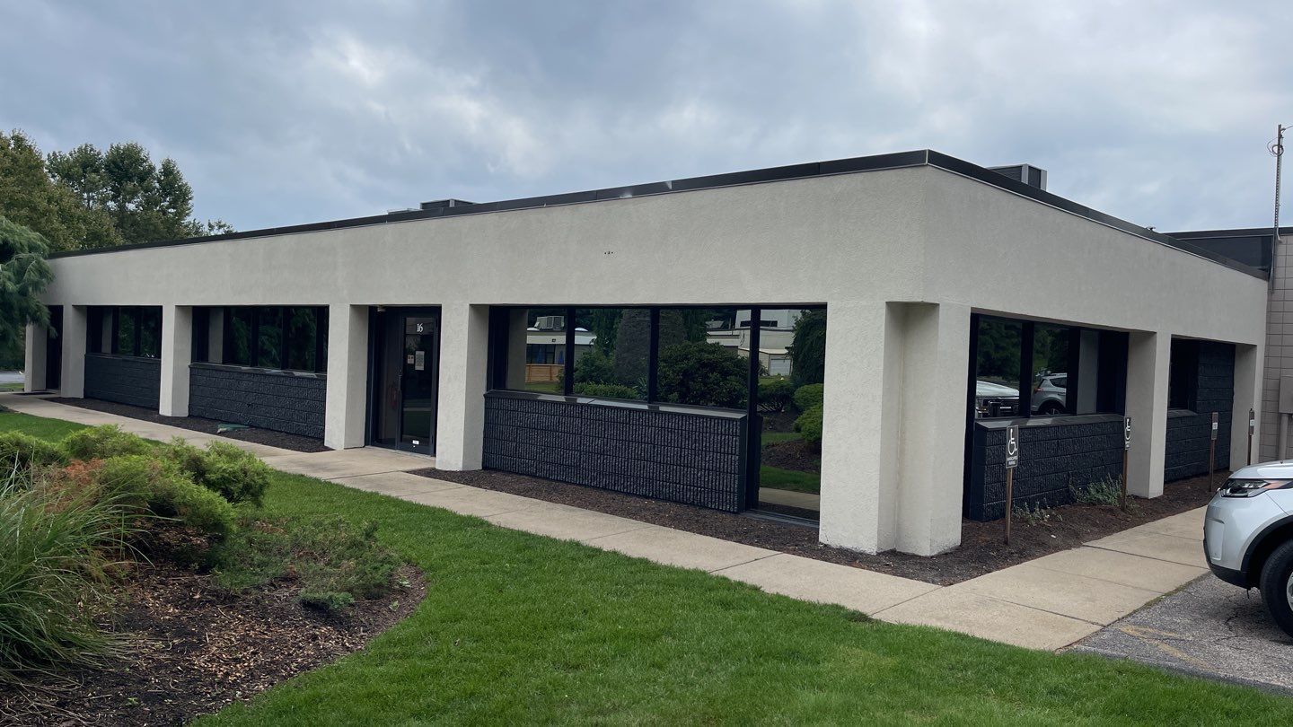 A low, one-story commercial building with a flat roof, large windows, and dark textured paneling below the windows.