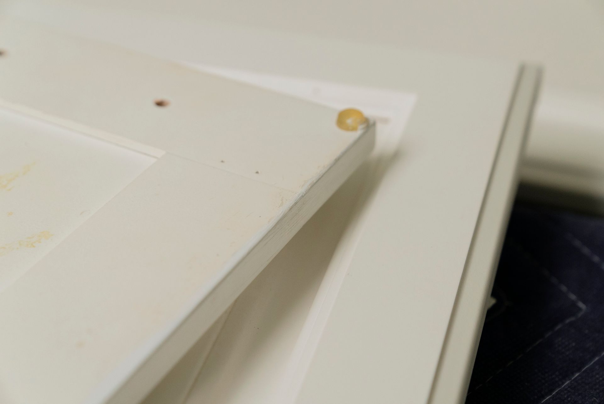 Close-up of two white cabinet doors, one slightly overlapping the other. A yellow bumper is attached to the top door.