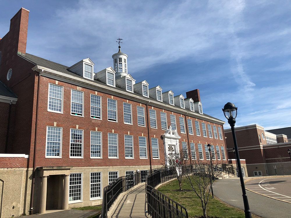 Red brick building with multiple windows under a blue sky. A black lamp post stands in the foreground.