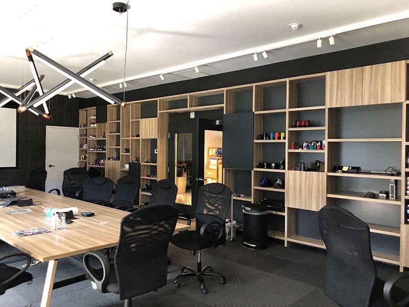 Conference room with a long wooden table, black chairs, and built-in wooden shelving on the back wall.  The room has a modern design.