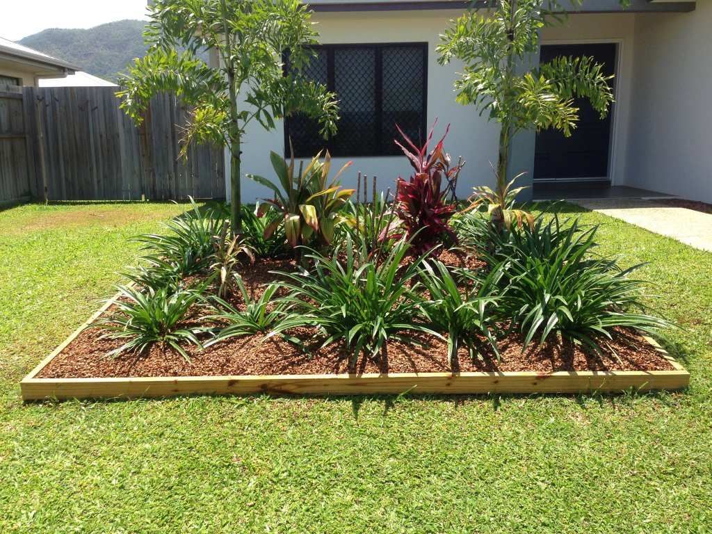 A Rectangular Flower Bed With Wood Edging, Filled With Green Plants and Mulch in Front of a House — Mow & Mulch Lawn & Garden Maintenance In White Rock, QLD