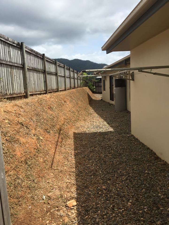 Gravel Path Beside a Beige Building, With a Dirt Embankment and Wooden Fence — Mow & Mulch Lawn & Garden Maintenance In White Rock, QLD