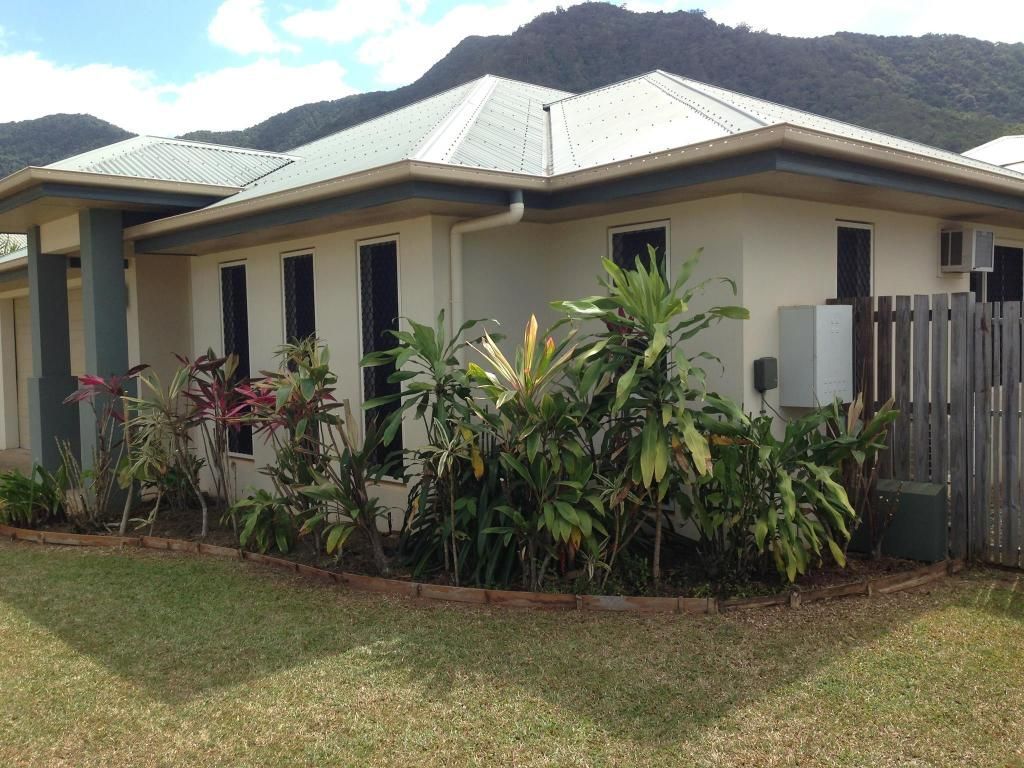 Green Lawn With a Garden Bed Featuring Shrubs, Mulch, and a Small Statue — Mow & Mulch Lawn & Garden Maintenance In White Rock, QLD