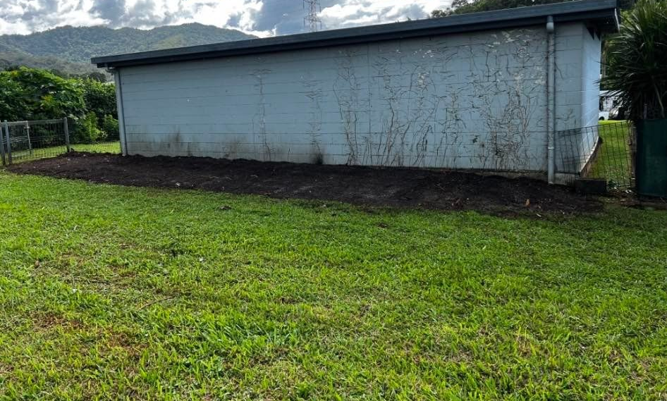 A White Building With Dark Soil in Front, Grass in Foreground — Mow & Mulch Lawn & Garden Maintenance In White Rock, QLD