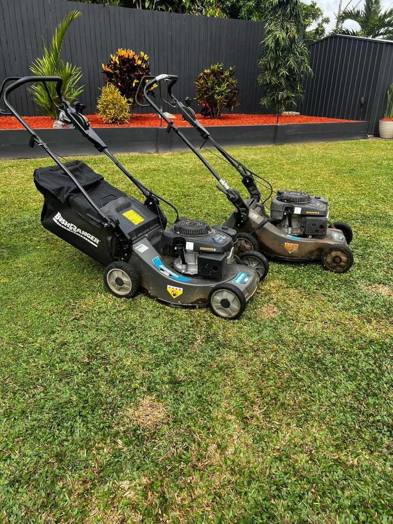 Two Lawn Mowers on Green Grass With Black Fence and Plants in the Background — Mow & Mulch Lawn & Garden Maintenance In White Rock, QLD