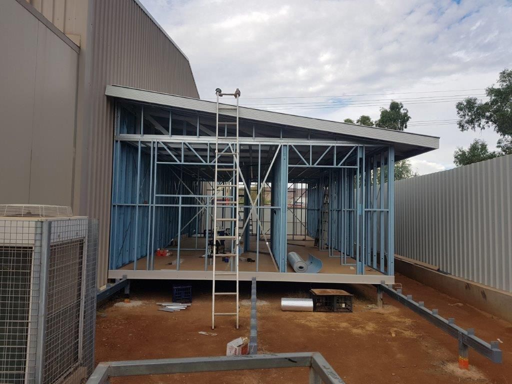 A building under construction with a ladder on top of it.