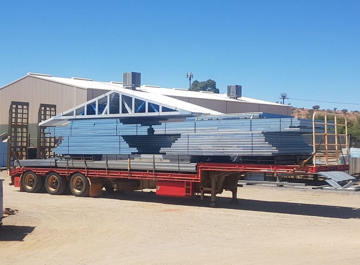 A truck is carrying a large stack of metal sheets on a trailer.
