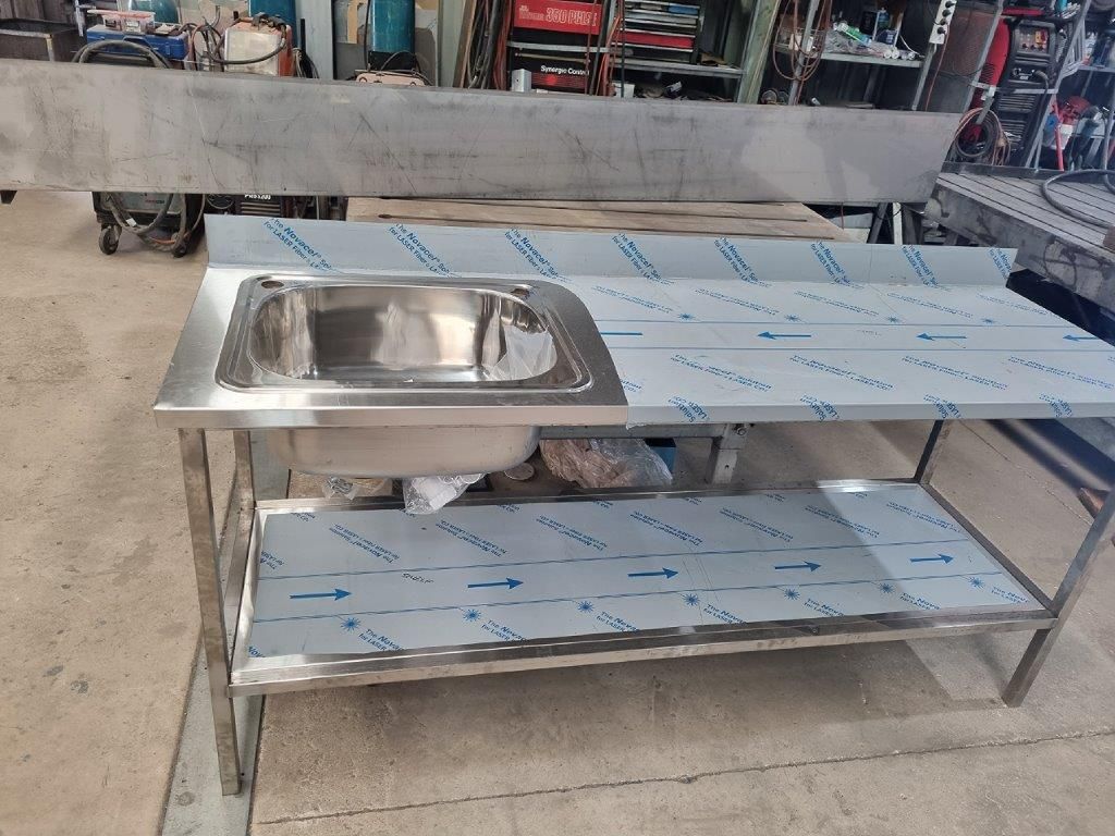 A stainless steel sink is sitting on top of a stainless steel table.
