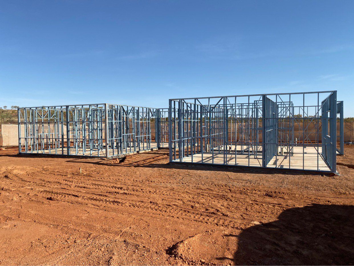 A house is being built in the middle of a dirt field.