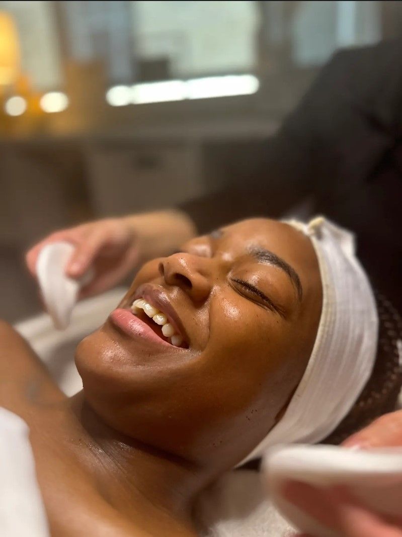 A woman is smiling while getting a facial treatment at a spa.