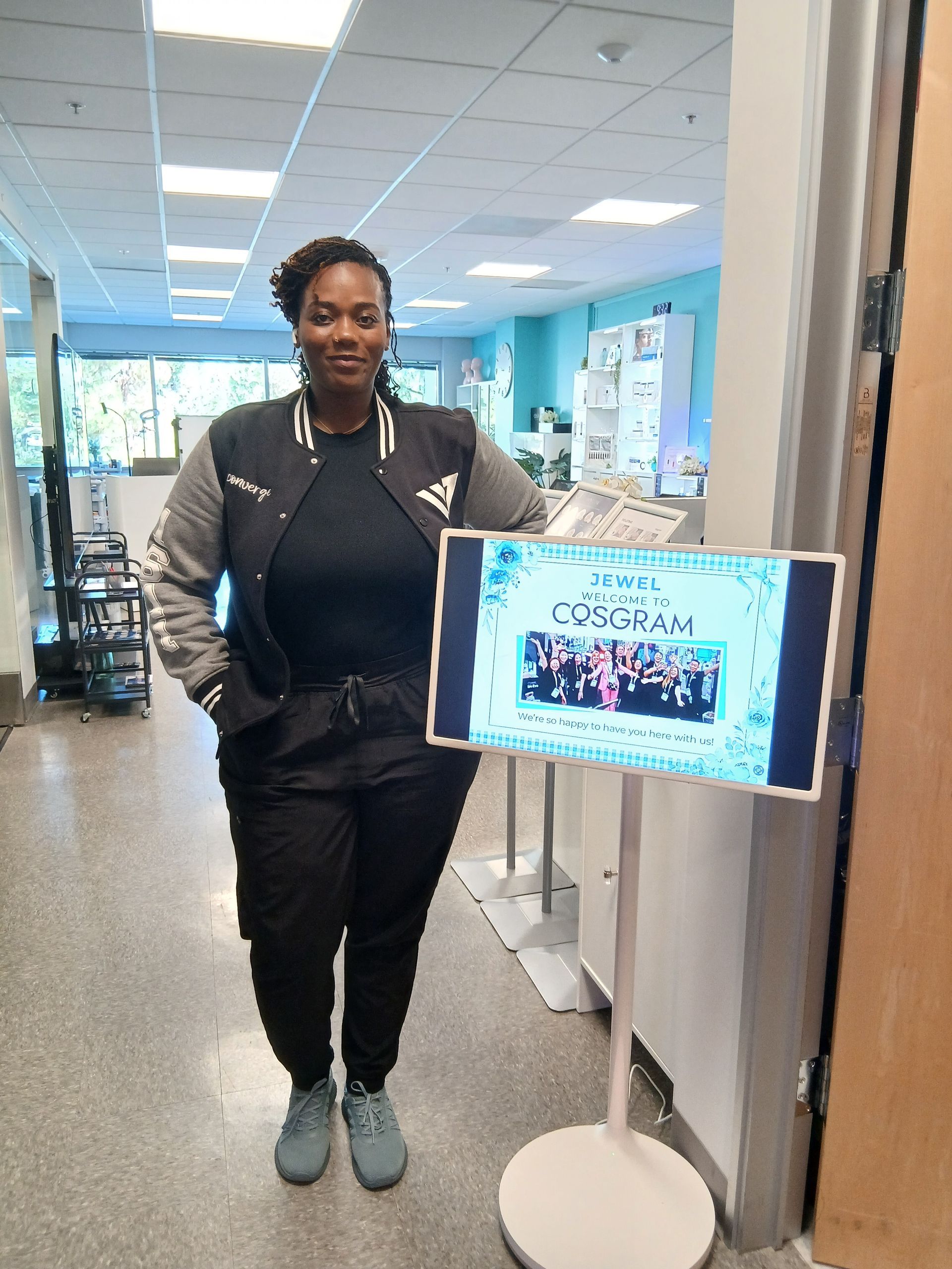 Woman in athletic wear stands next to a digital sign in a hallway.
