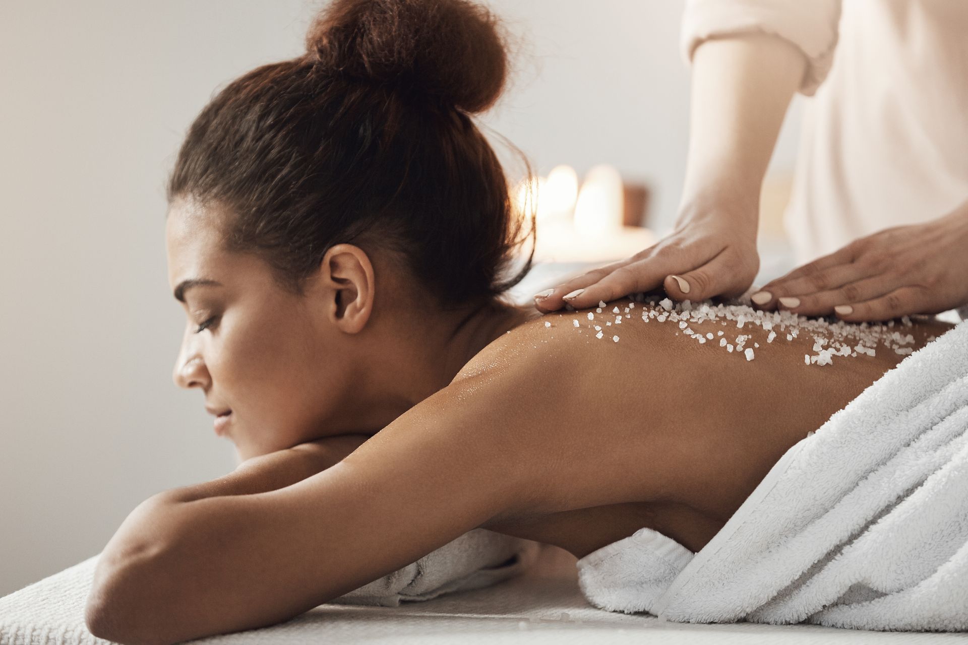 A woman is getting a massage with sea salt on her back.