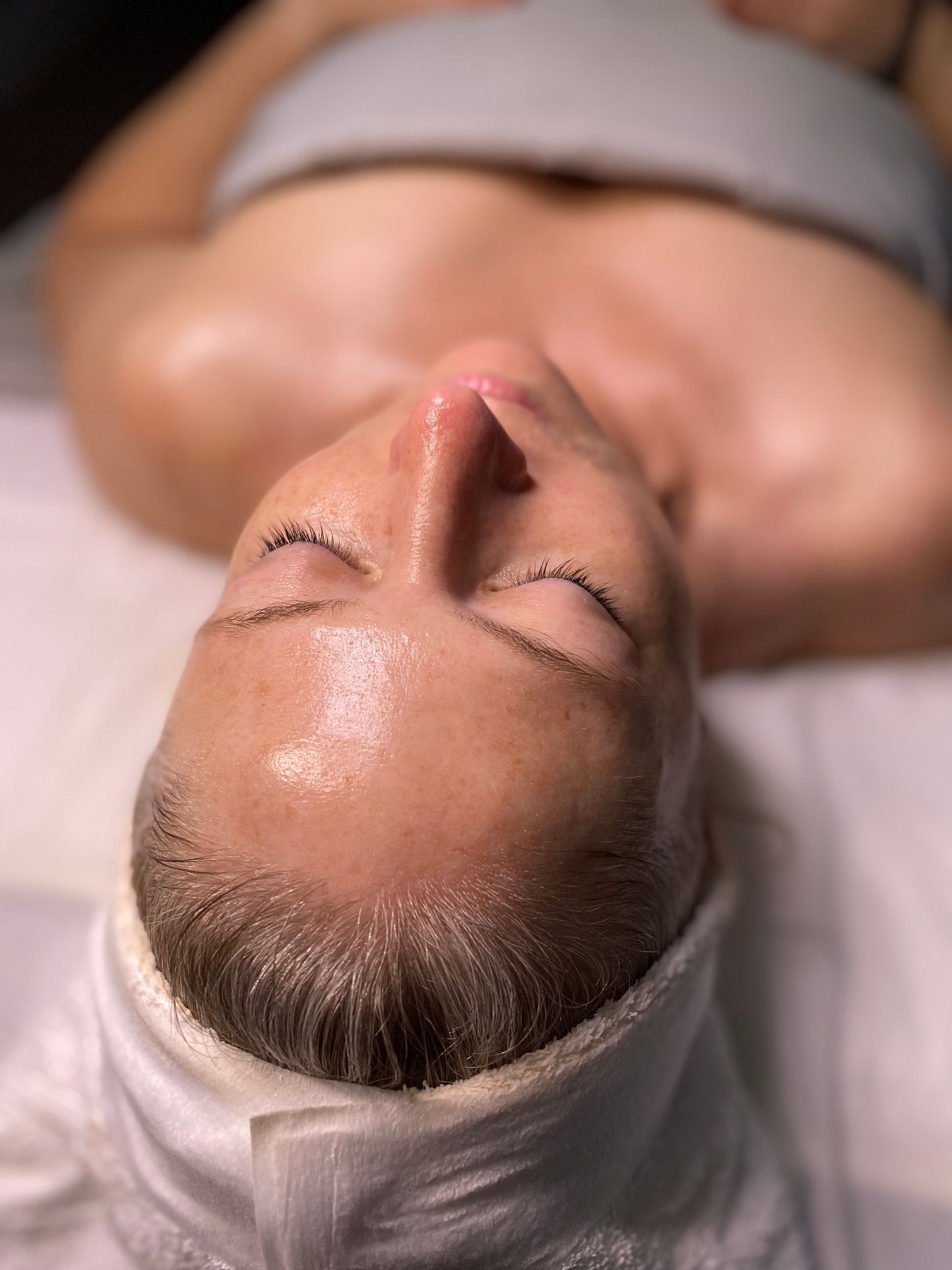 A woman is lying on the ed getting a facial treatment