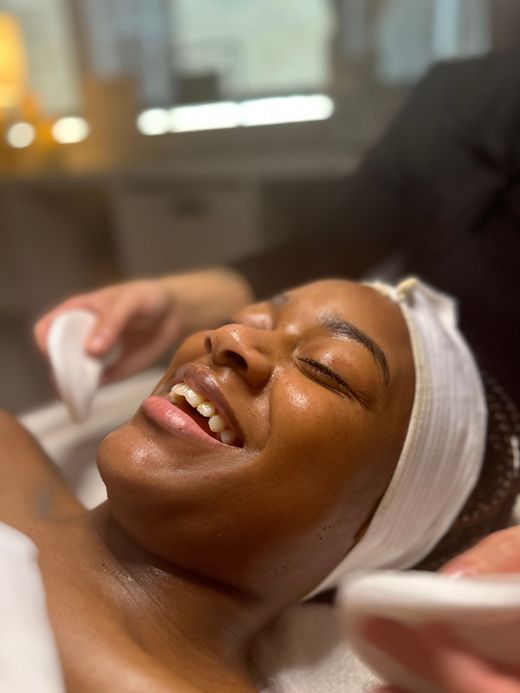 Woman receiving facial massage at a spa, with hands on her face.