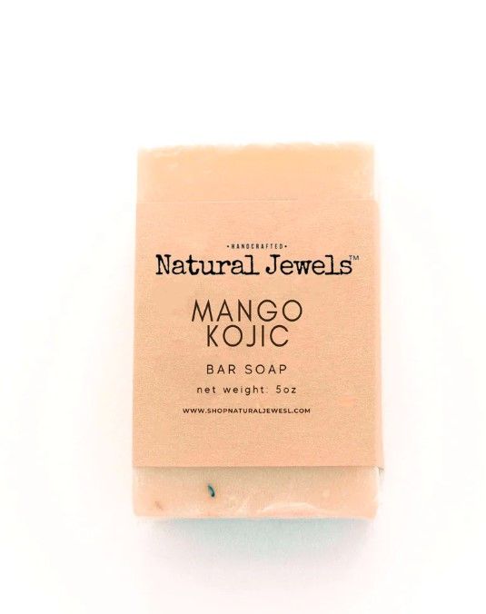 A natural jewels mango kojic bar soap is sitting on a white surface.