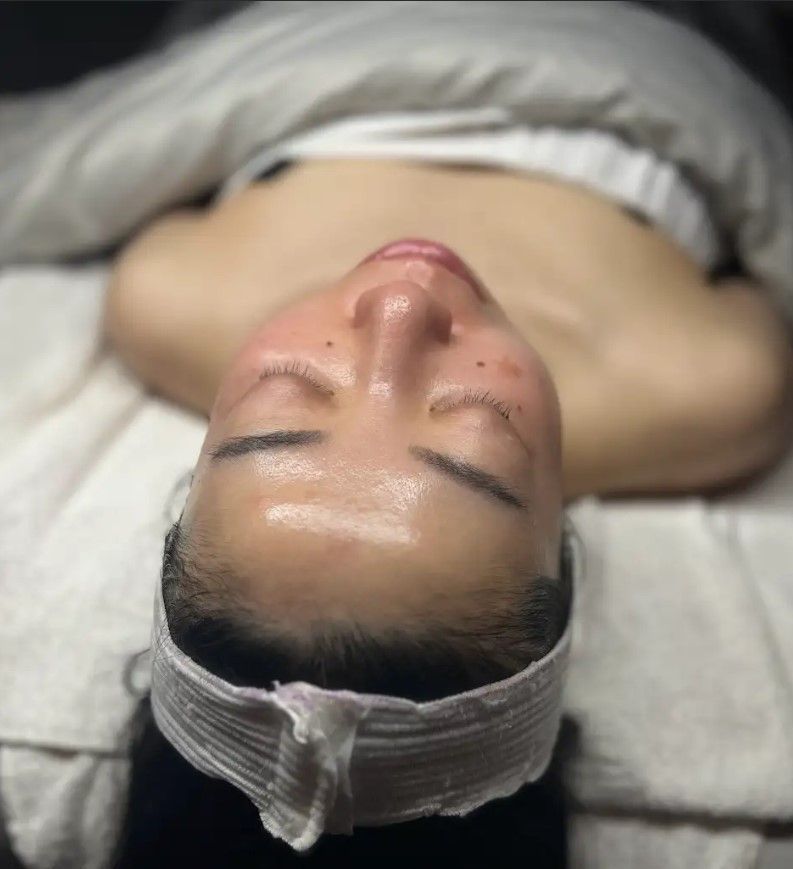 A woman is laying on a bed with her eyes closed and a towel around her head.