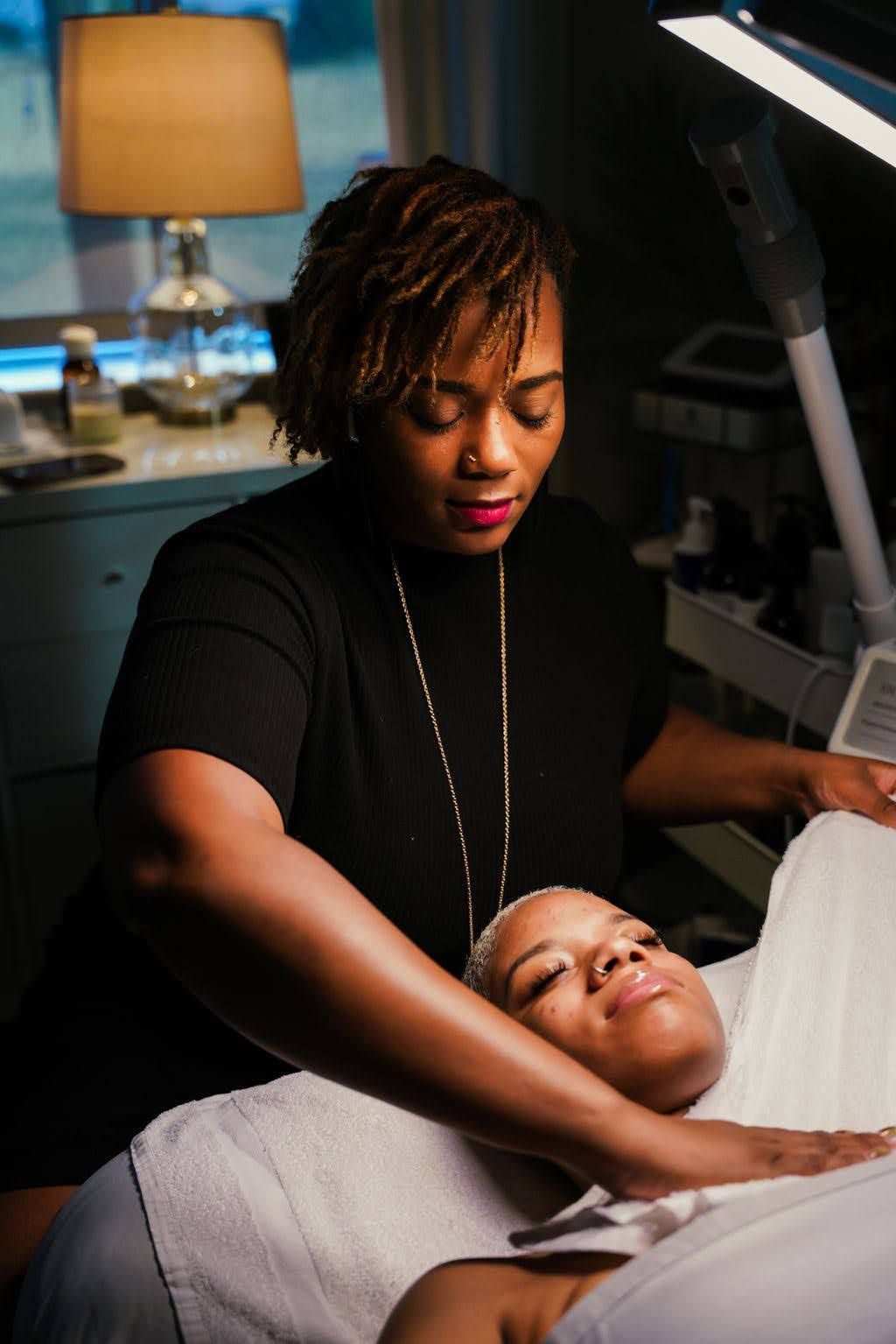 A woman is examining a woman 's face under a magnifying glass in a beauty salon.