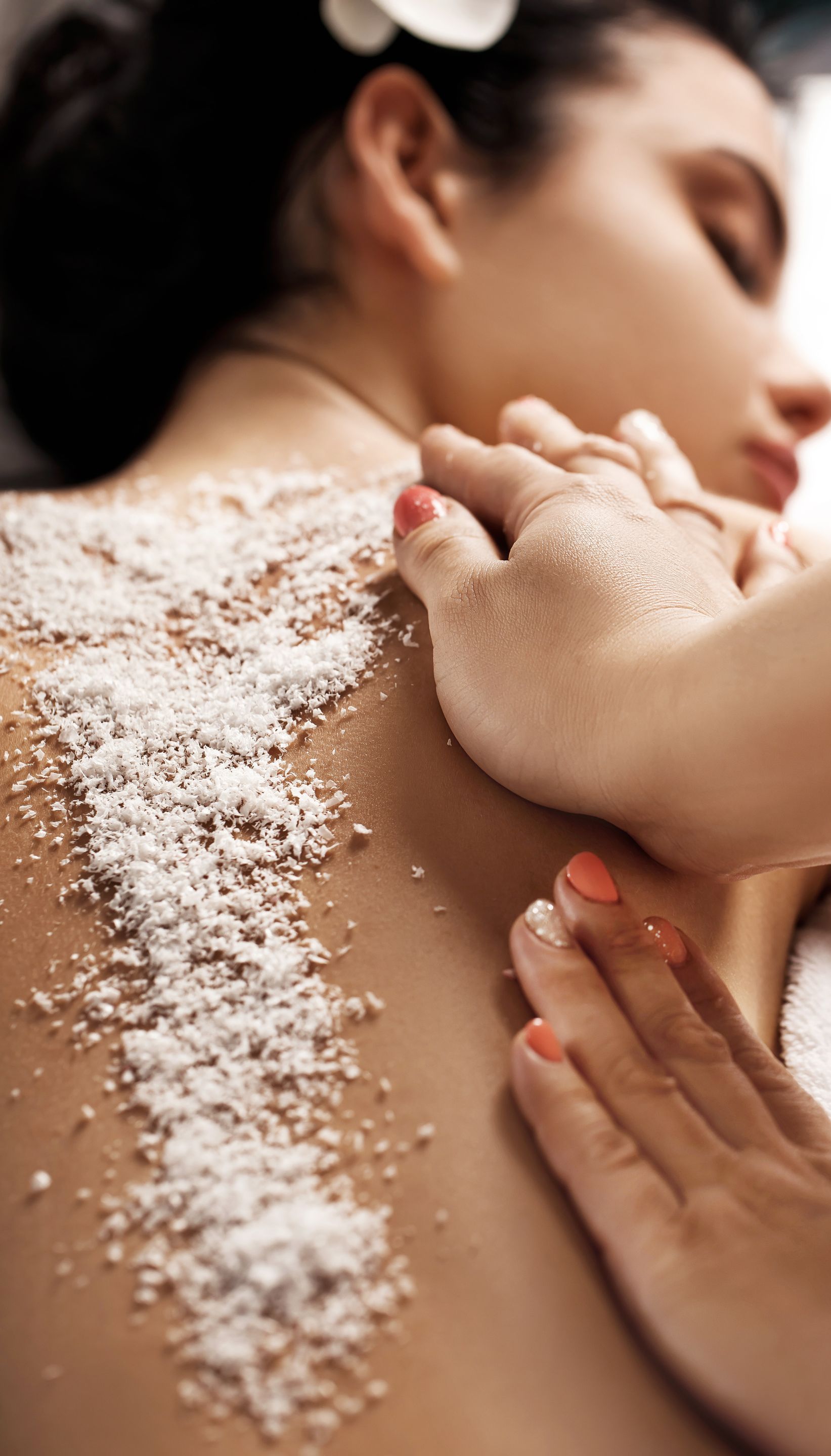 A woman is getting a massage with sea salt on her back.