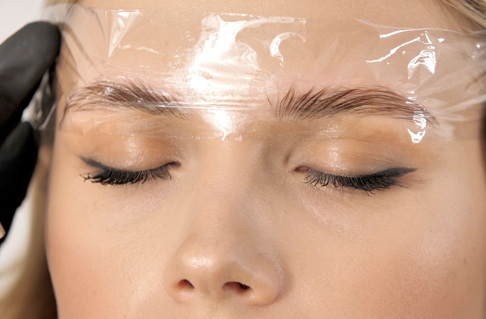 a close up of a woman 's face with plastic covering her eyebrows .