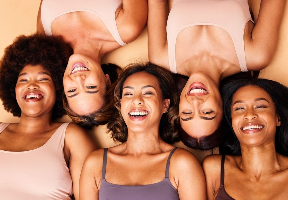 A group of women are laying on their backs and smiling.