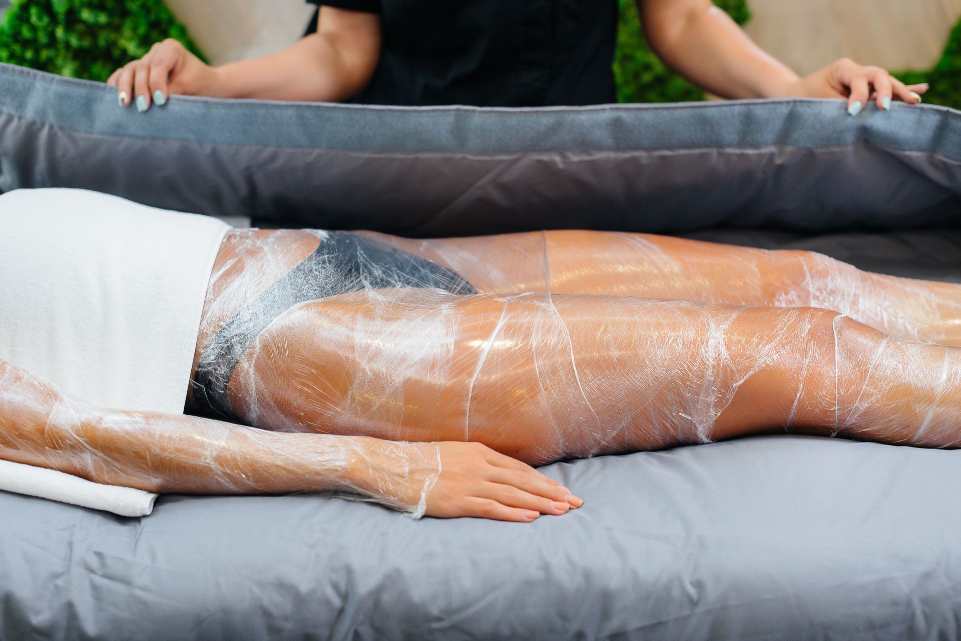 A woman is laying on a bed wrapped in plastic wrap.