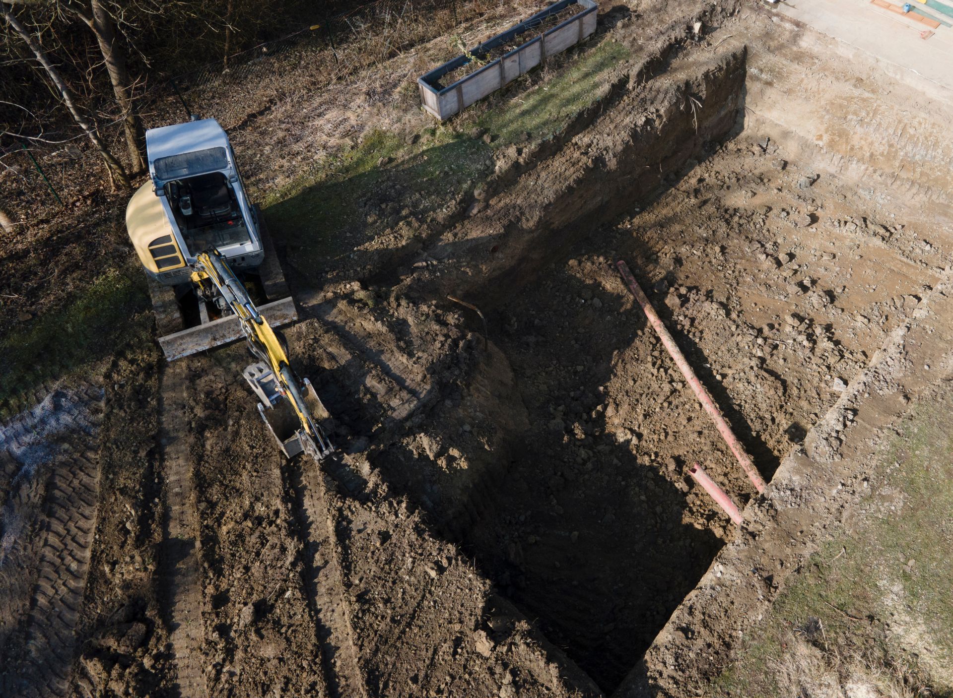Aerial view of a construction site showing excavation for a new swimming pool installation.
