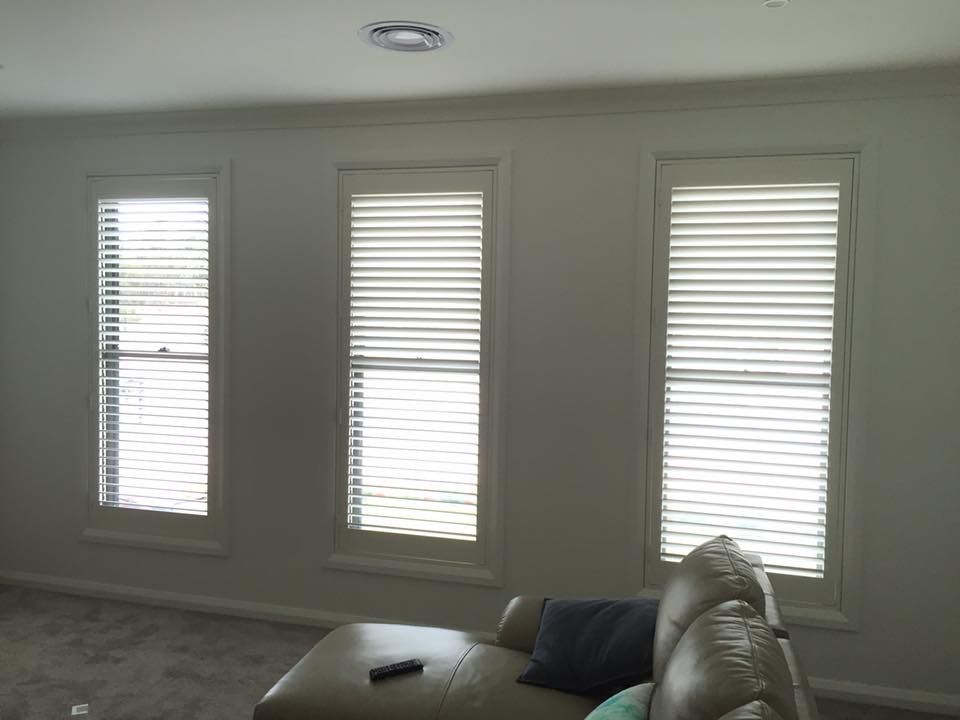 A Living Room With A Couch And Three Windows With Blinds — Spring Crest Blinds, Awnings & Security Doors in Shepparton, VIC