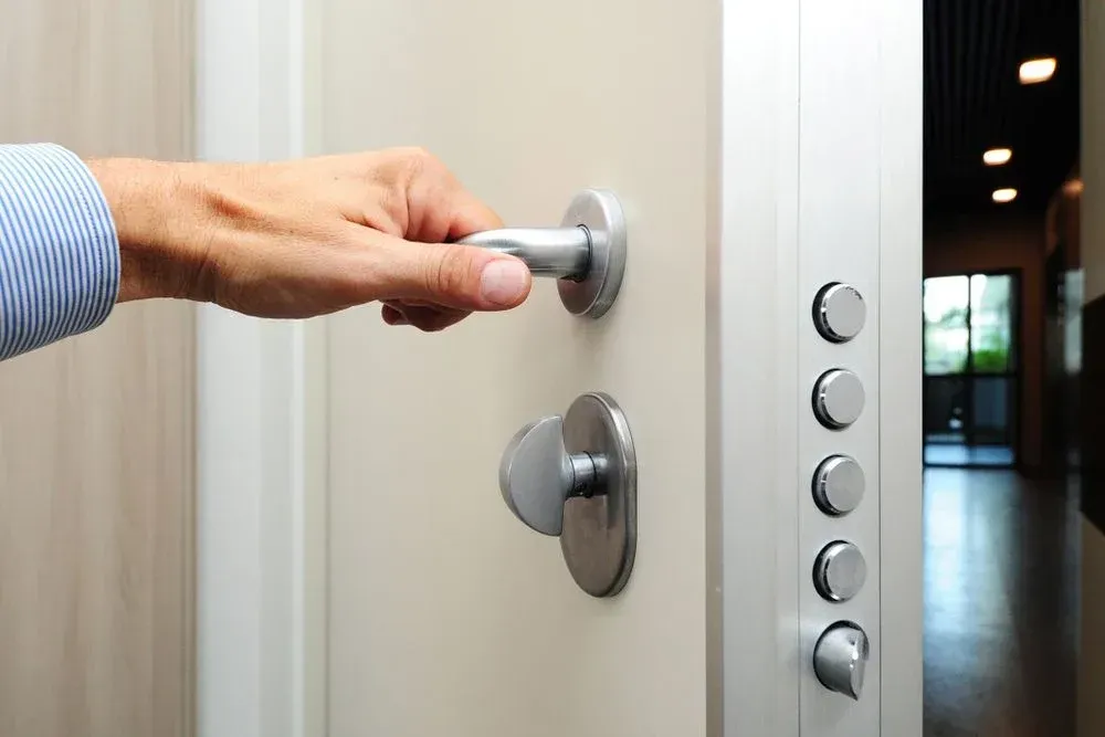 A Person Is Opening A Door With Their Hand — Spring Crest Blinds, Awnings & Security Doors in Ballarat, VIC