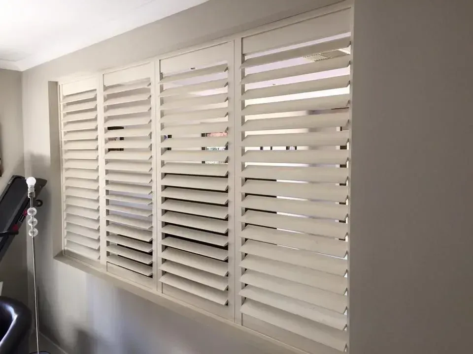 A Room With A Treadmill And A Window With Shutters On It — Spring Crest Blinds, Awnings & Security Doors in Melbourne, VIC 