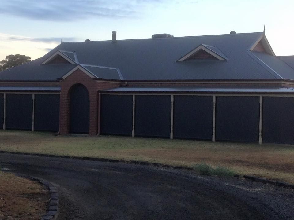 A Large House With A Gray Roof And Black Garage Doors — Spring Crest Blinds, Awnings & Security Doors in Shepparton, VIC