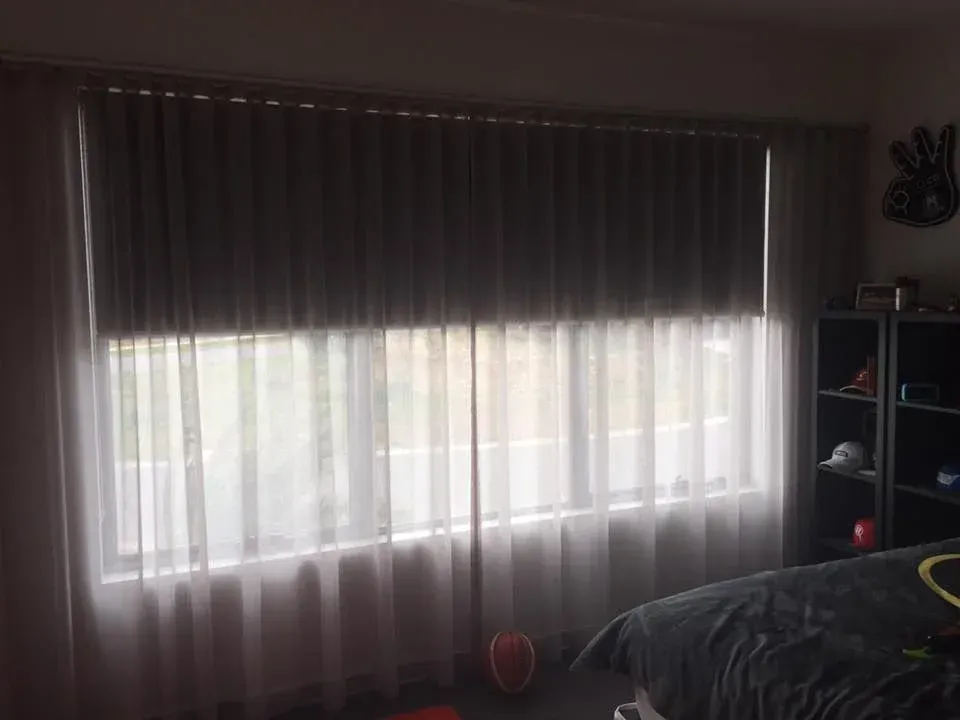 A Bedroom With A Bed And A Window With Curtains — Spring Crest Blinds, Awnings & Security Doors in Golden Square, VIC