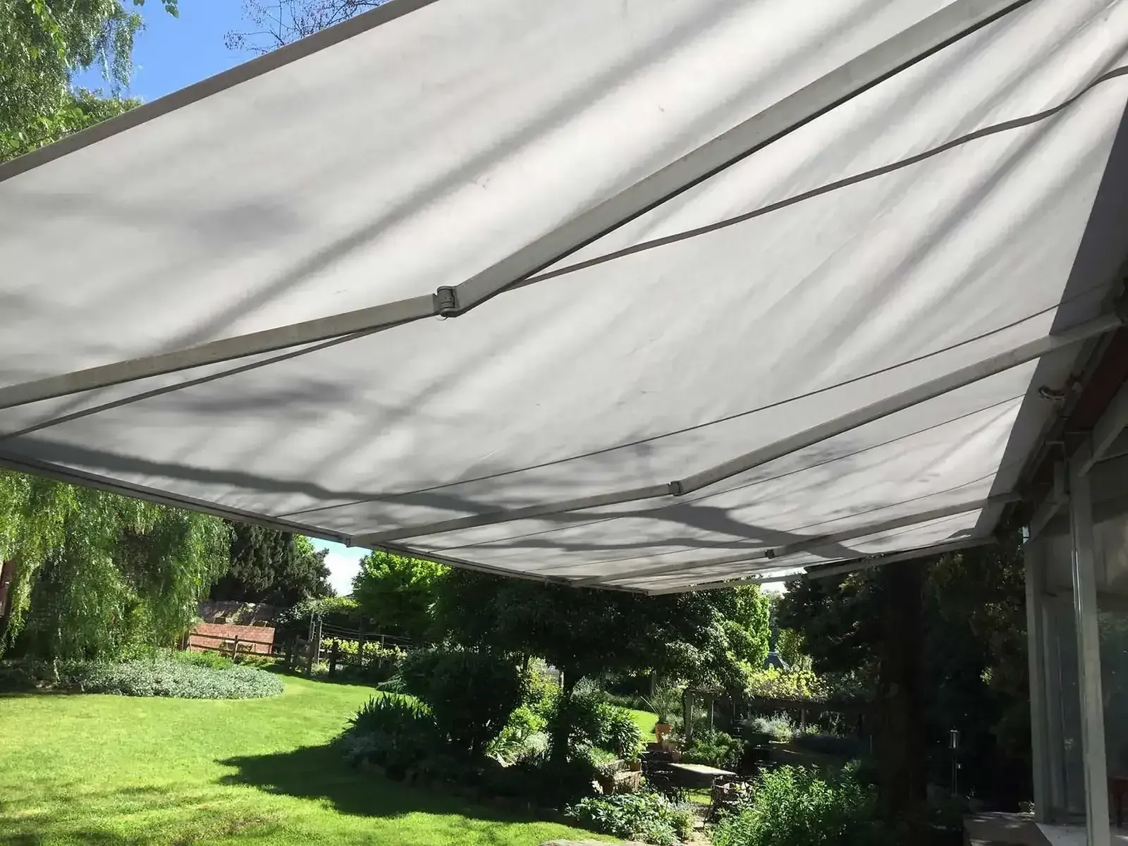A Large White Awning Is Hanging Over A Lush Green Field  — Spring Crest Blinds, Awnings & Security Doors in Melbourne, VIC