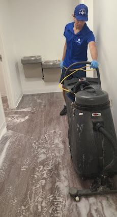 A man is cleaning a floor with a vacuum cleaner.