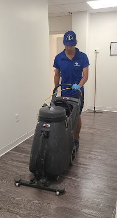 A man is cleaning a wooden floor with a vacuum cleaner.