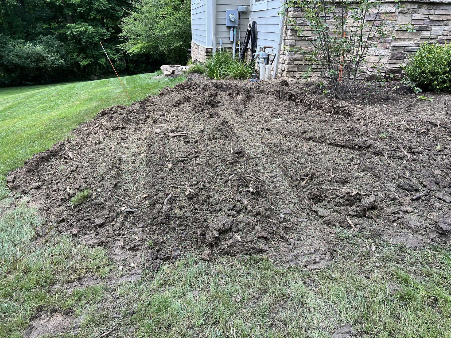 A pile of dirt is sitting in the grass in front of a house.