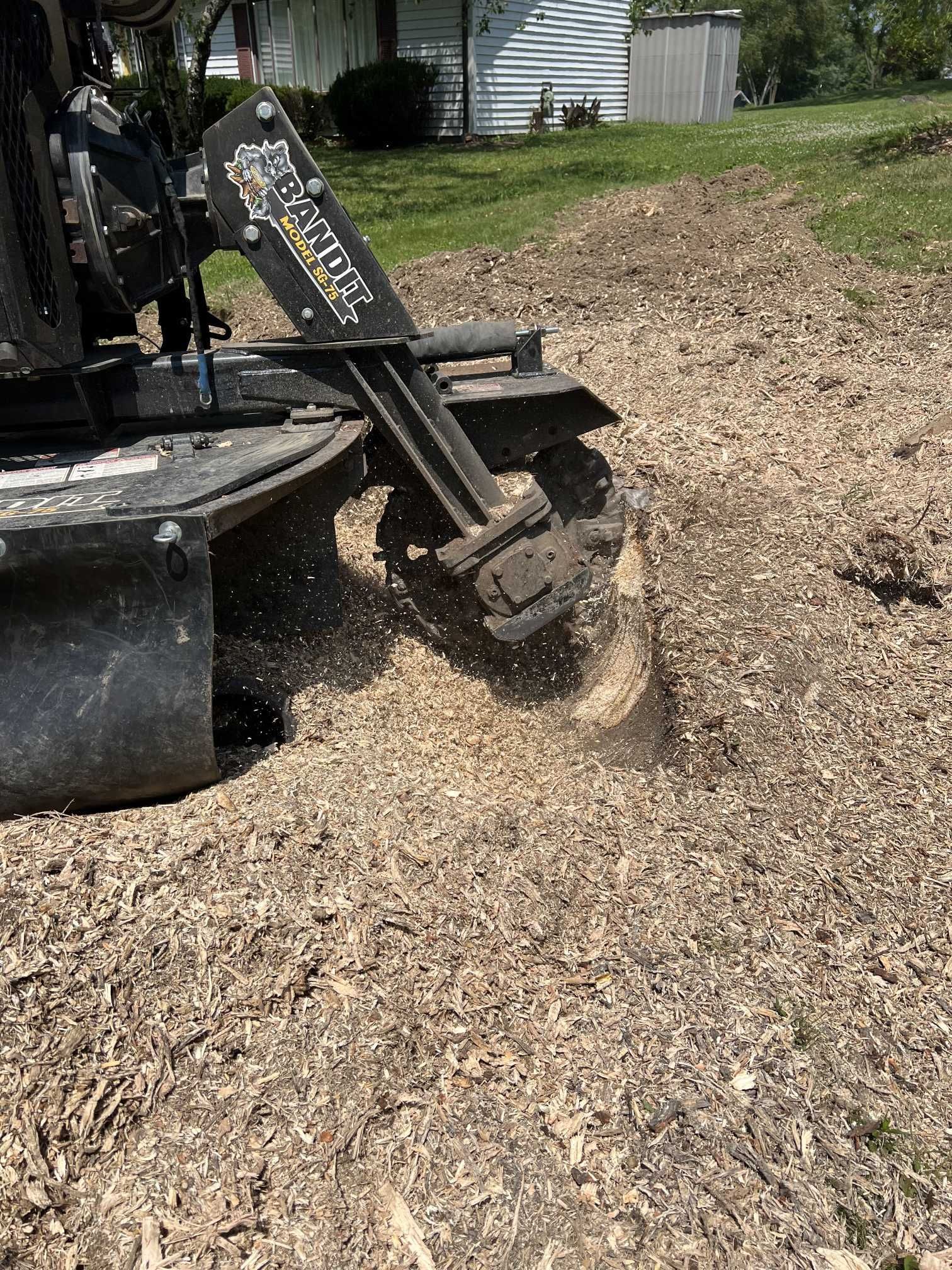 A machine is stump grinding a tree stump in a yard.