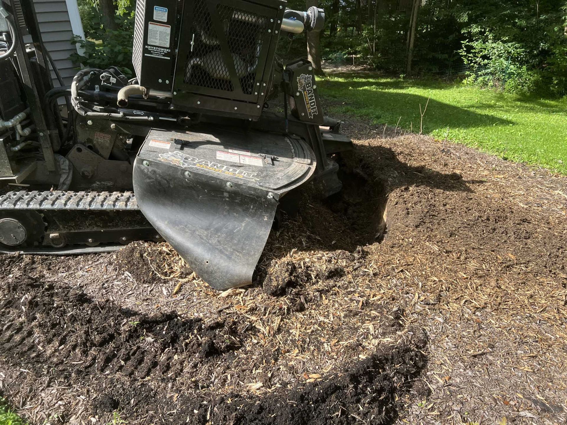 A stump grinder is working on a tree stump in a yard