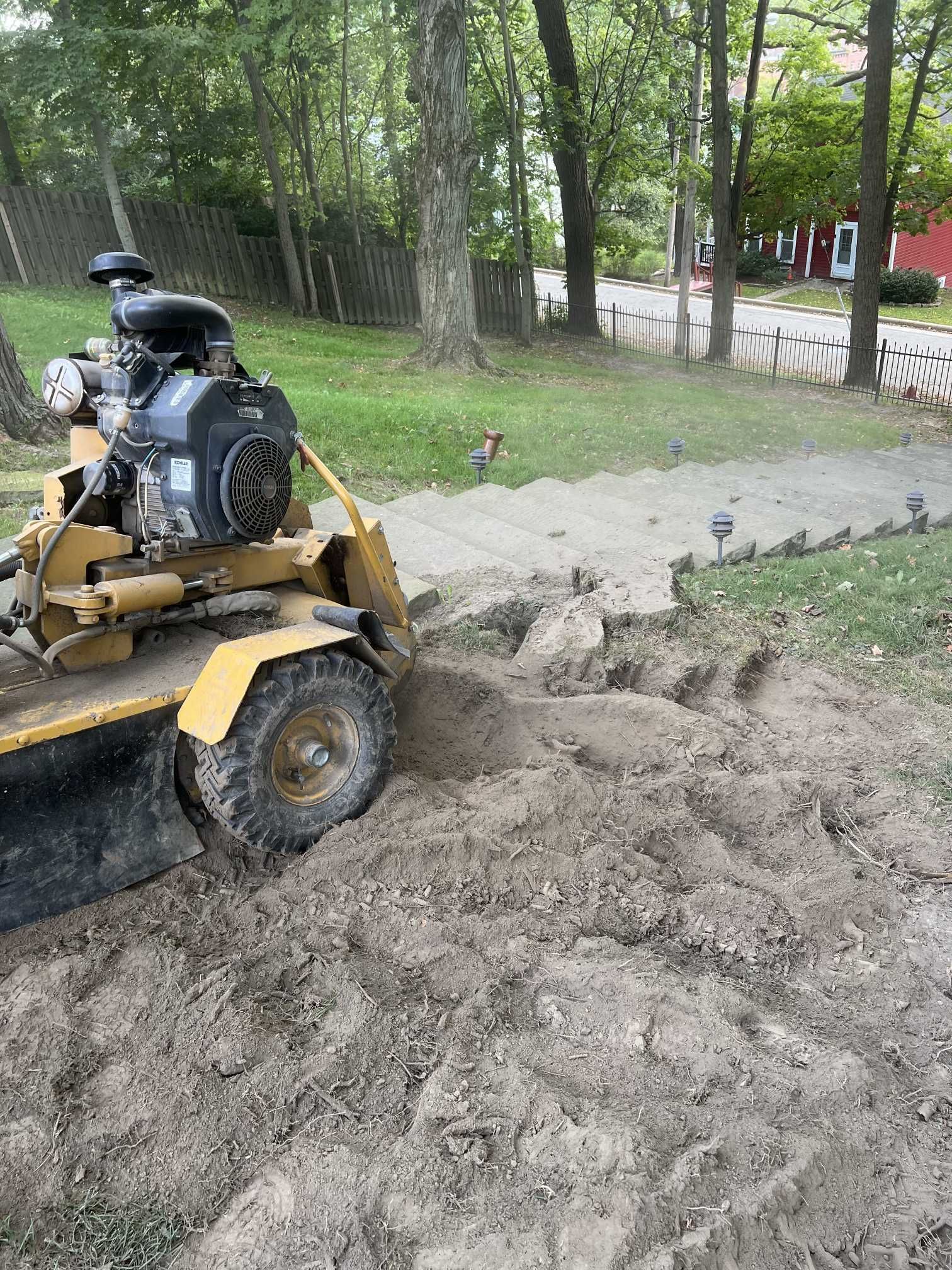 A stump grinder is digging a hole in the ground in a yard.